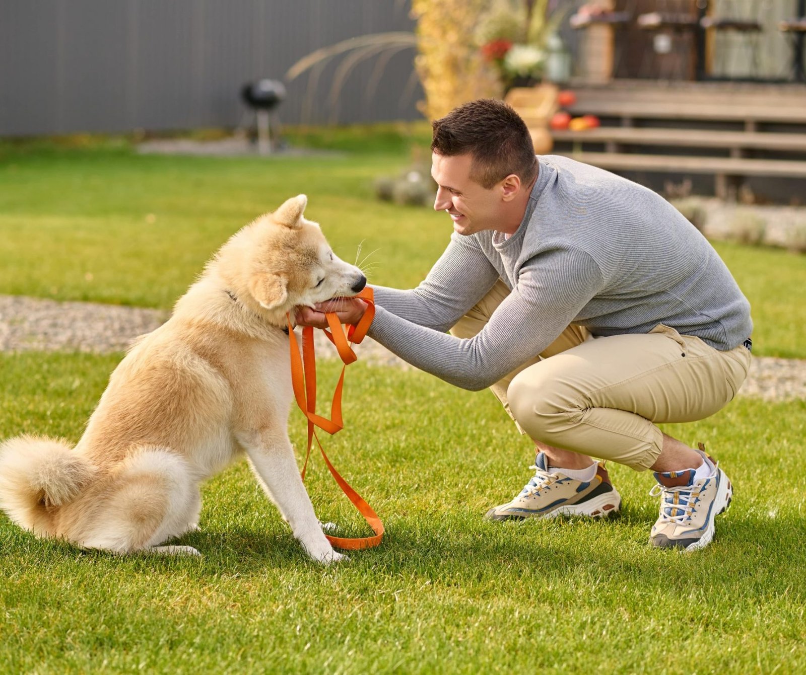 smart-dog-sideways-camera-joyful-young-adult-man-crouching-touching-friendly-smart-dog-with-leash-near-country-house-autumn-day-min